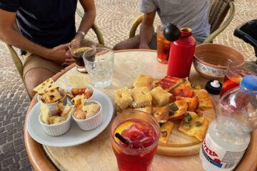 An assortment of Italian aperitivo food including pizza, focaccia and cocktails at a bar in Turin, Italy