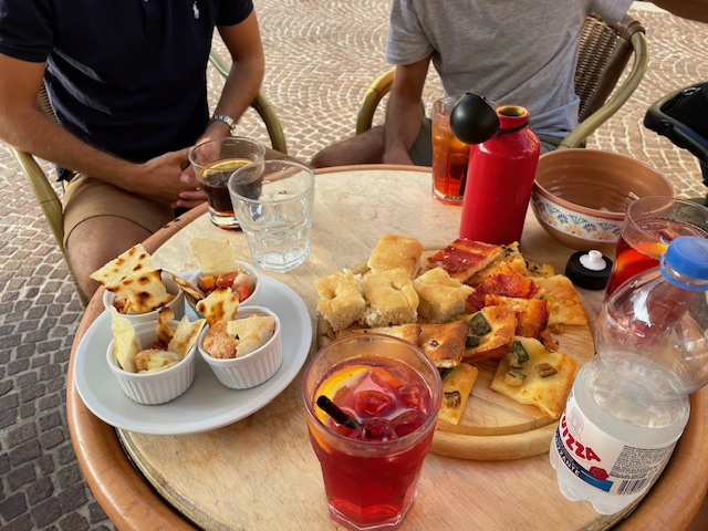 An assortment of Italian aperitivo food, including pizza sllices, focaccia and cocktails at a bar in Turin, Italy